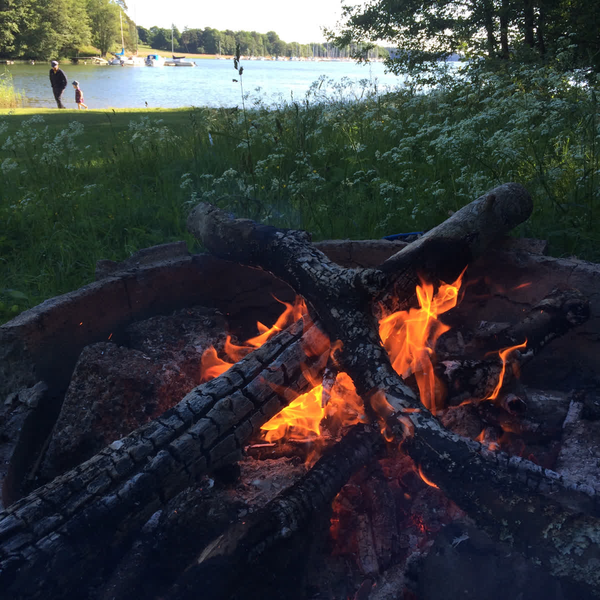 A campfire with a lake in the background.